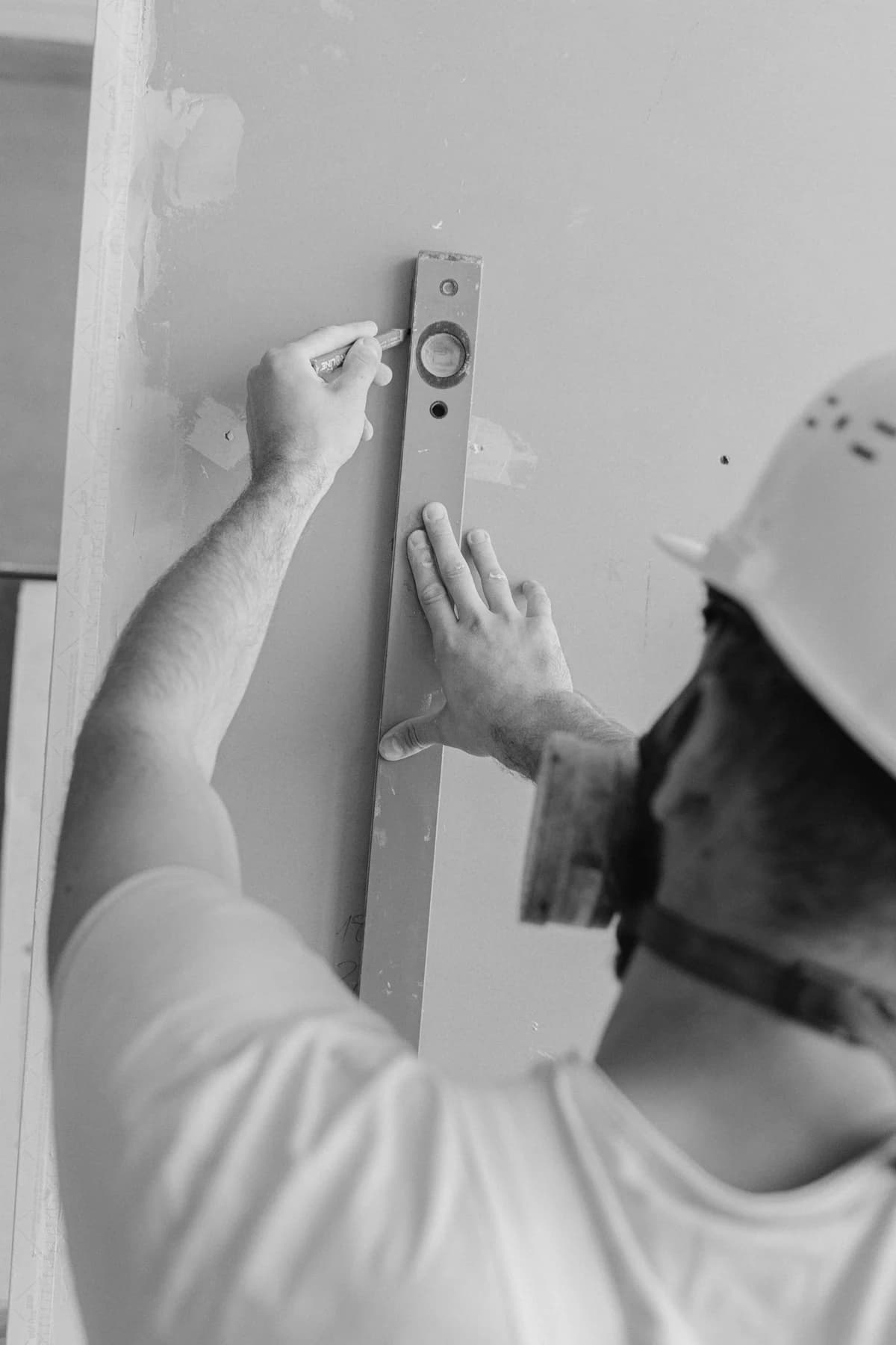A trade professional checking an interior wall with a level.